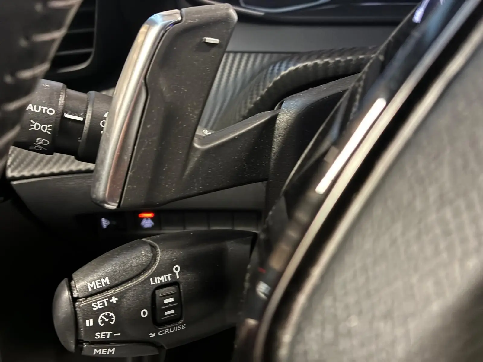 Gros plan sur la commande de régulateur de vitesse et palettes au volant du Peugeot 2008 gris, intérieur noir.