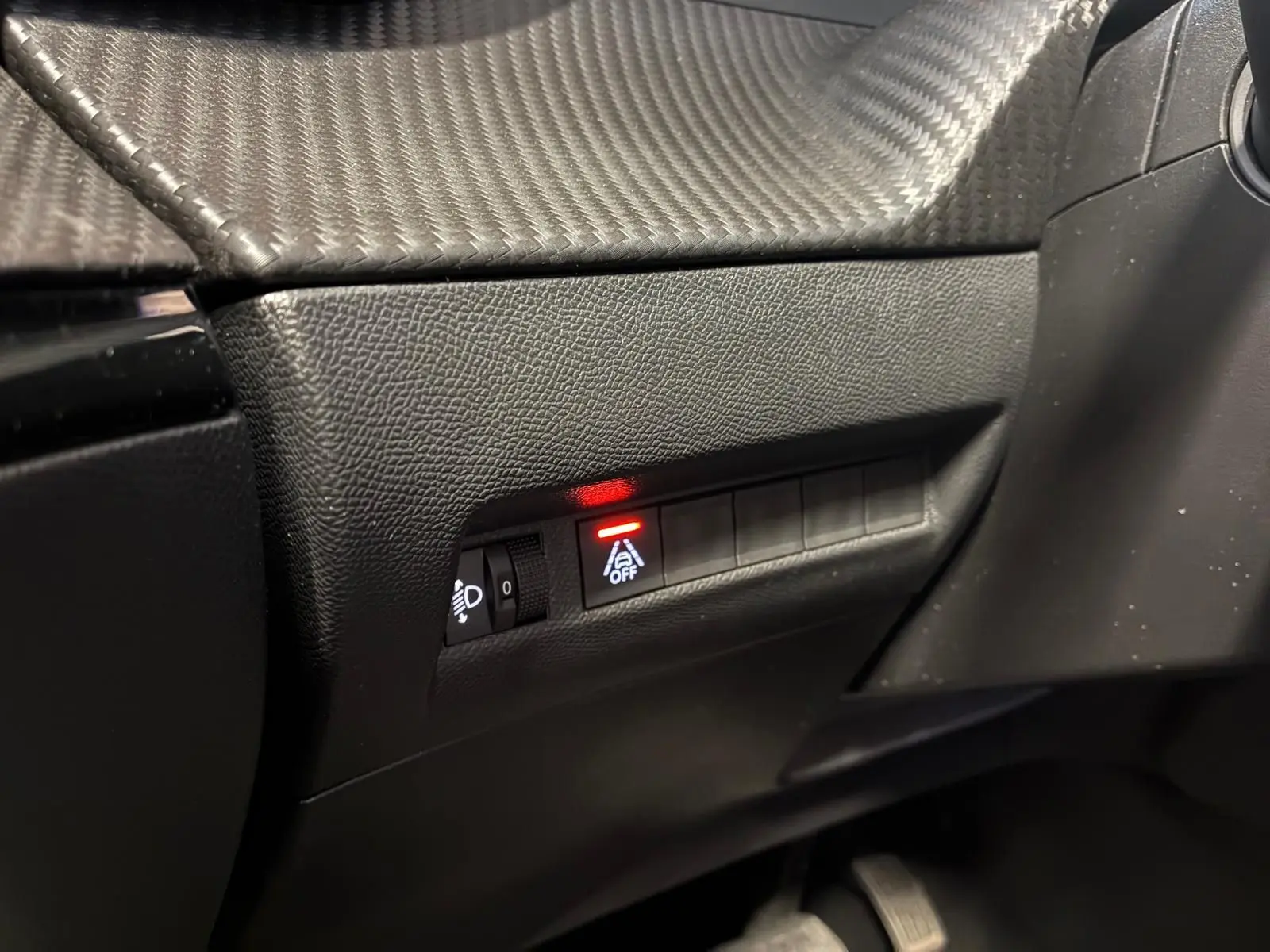 Gros plan sur les commandes noires du tableau de bord côté conducteur du Peugeot 2008 gris, avec témoin lumineux rouge actif.