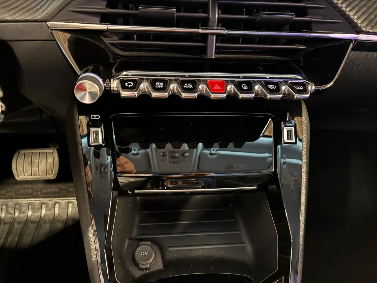 Vue rapprochée de la console centrale noire brillante du Peugeot 2008 1.5 BlueHDi 130, avec boutons de commande alignés.