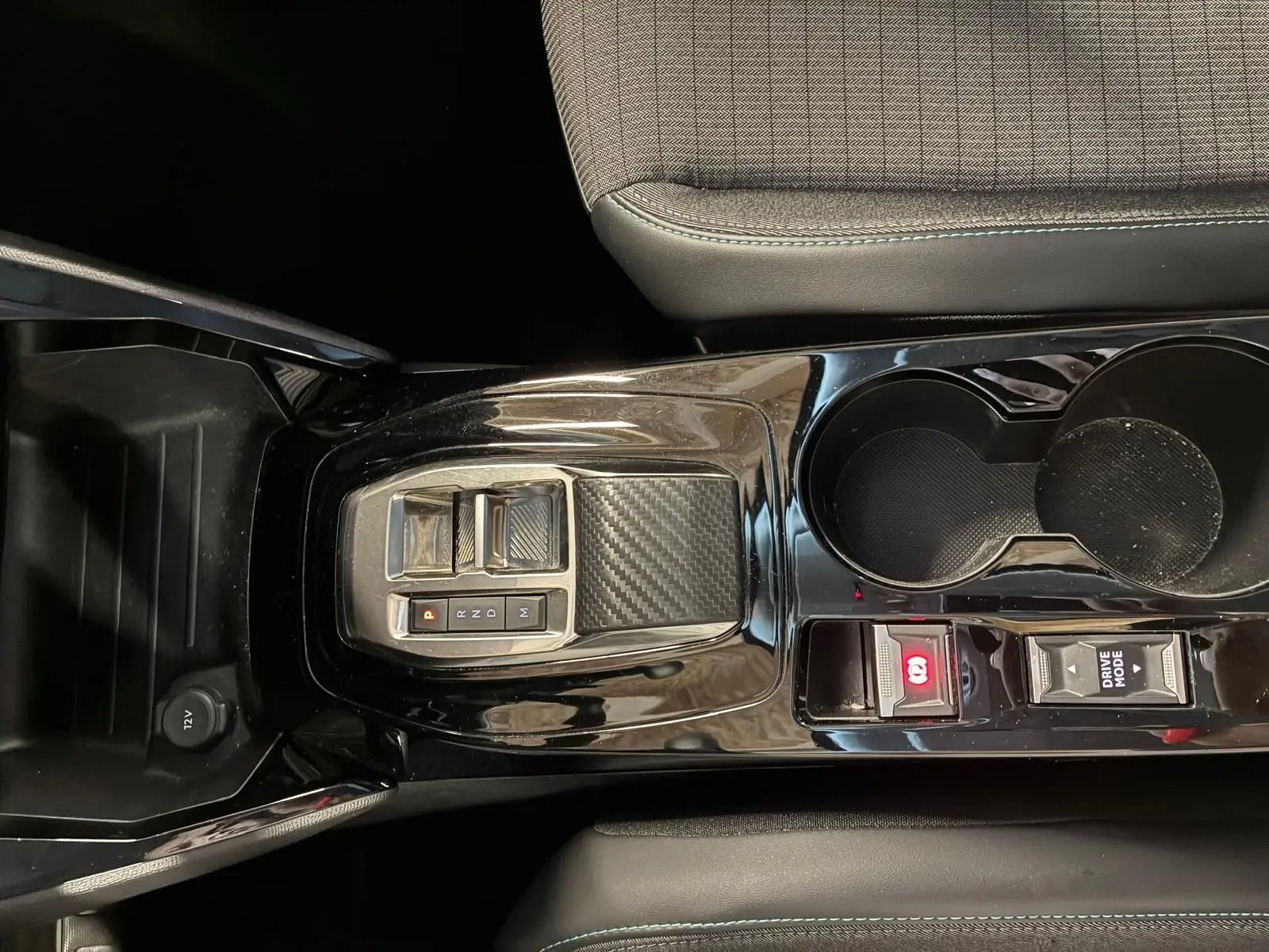 Vue plongeante sur la console centrale noire brillante du Peugeot 2008 gris, avec levier de vitesses électronique et porte-gobelets.