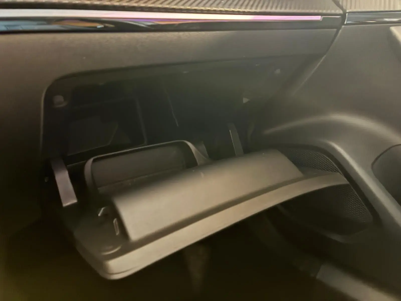 Gros plan sur la boîte à gants ouverte côté passager de la Peugeot 2008 gris 2022, intérieur noir.