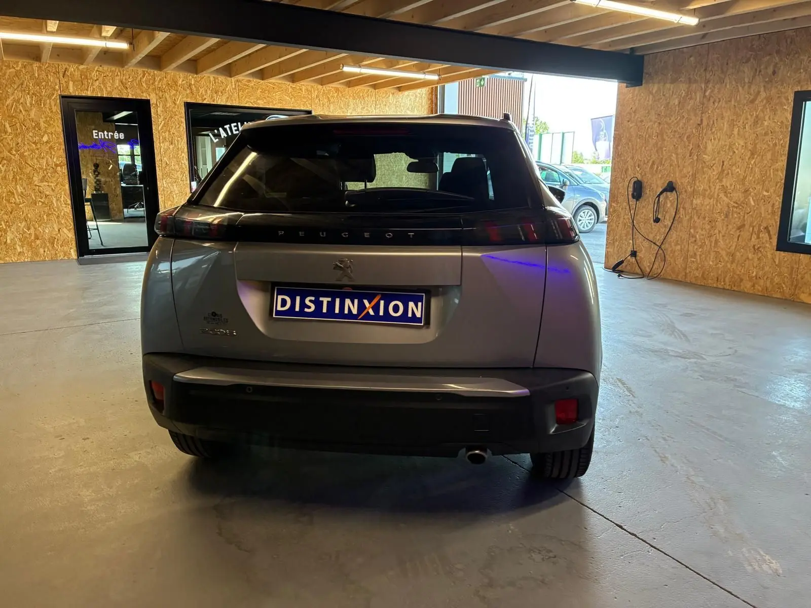Vue arrière d’un Peugeot 2008 gris 2022 dans un garage, avec plaque d’immatriculation Distinxion visible.
