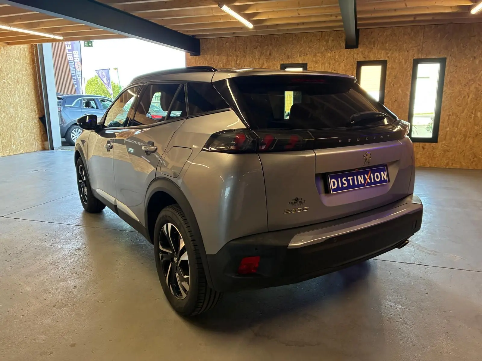 Peugeot 2008 gris en 3/4 arrière droit dans un garage, avec toit noir et feux arrière sombres distinctifs.