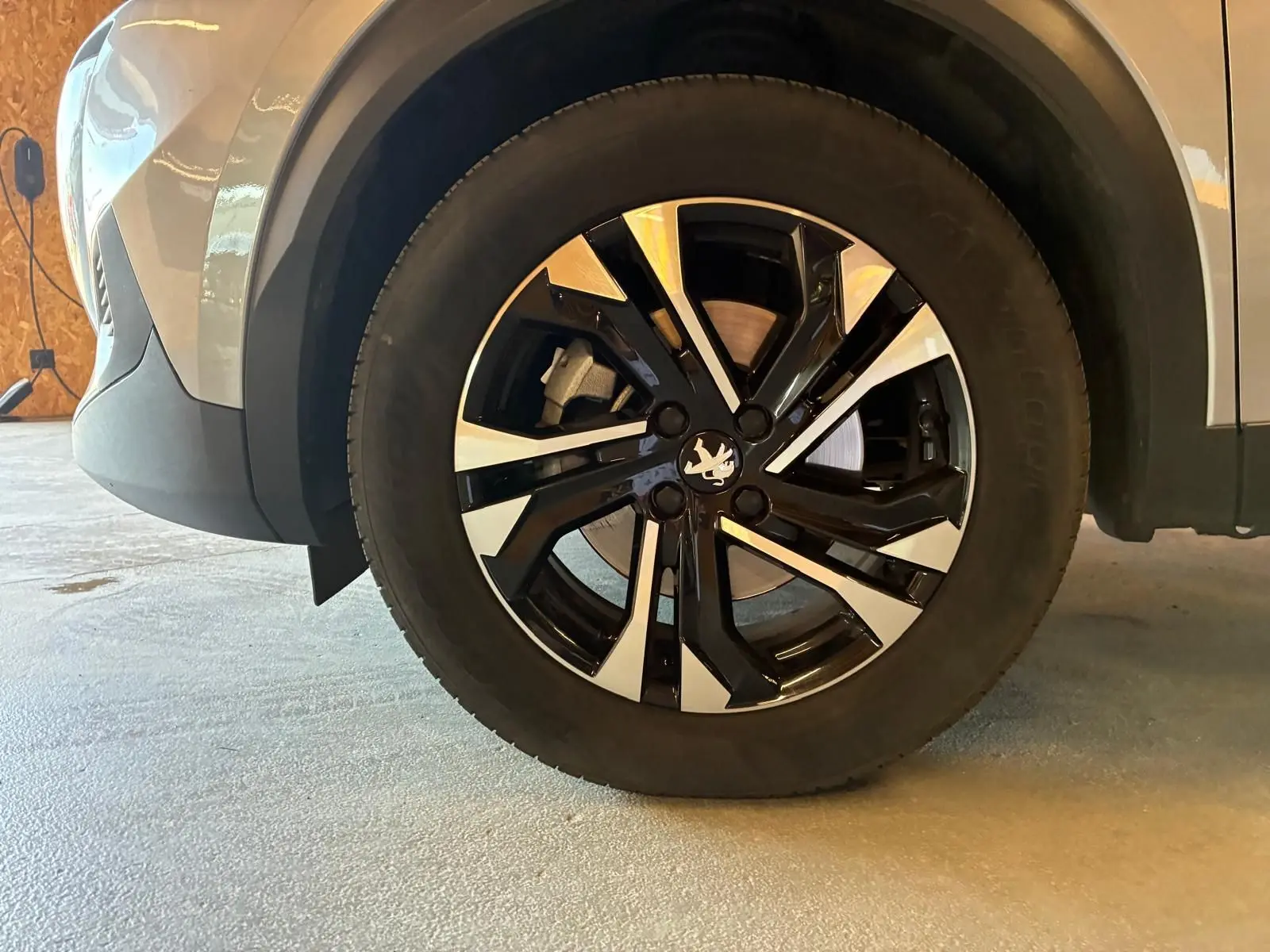 Gros plan sur la roue avant droite du Peugeot 2008 gris 2022, avec jante alliage noire et argentée au design moderne.