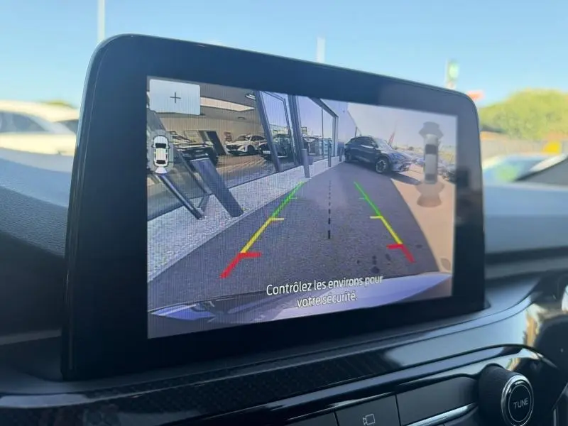 Écran tactile intérieur montrant la caméra de recul du Ford Kuga gris Solar, vue arrière avec lignes de guidage colorées.
