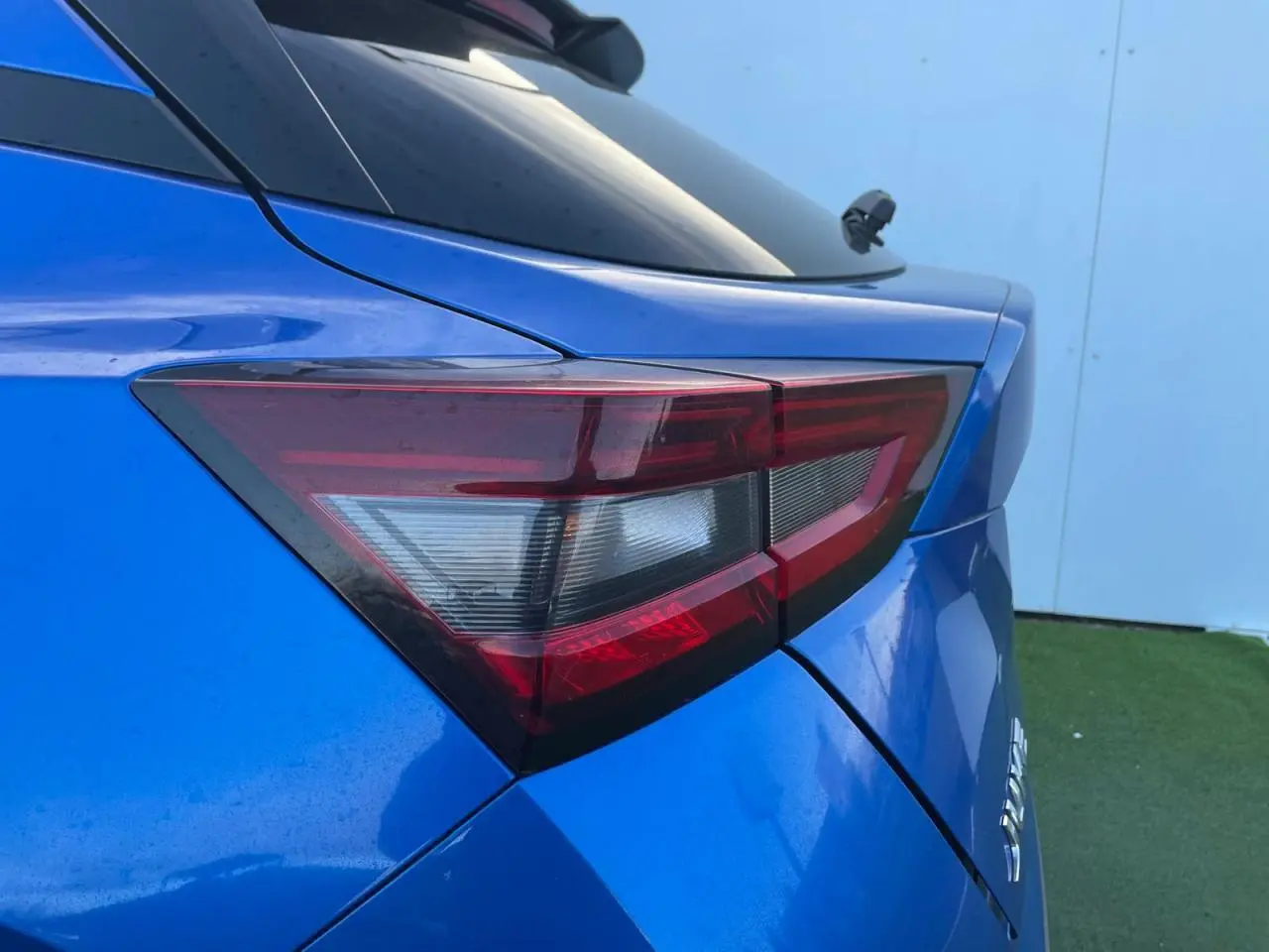 Gros plan sur le feu arrière droit bleu magnetic du Nissan Juke II 2024 avec antenne aileron de requin noire.