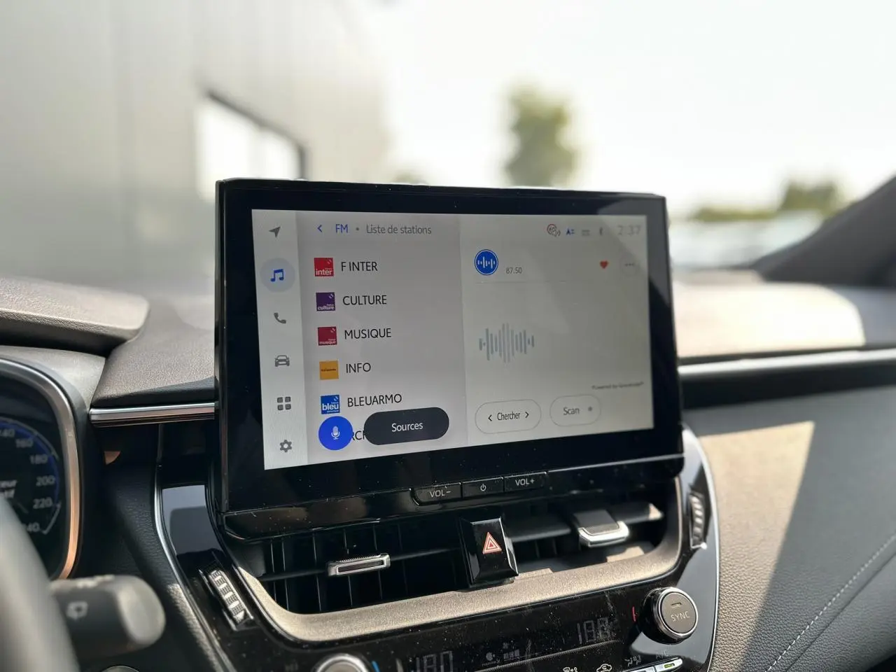Écran tactile central de la Toyota Corolla Touring Sport 1.8 Hybrid 2025 affichant la liste des stations radio.