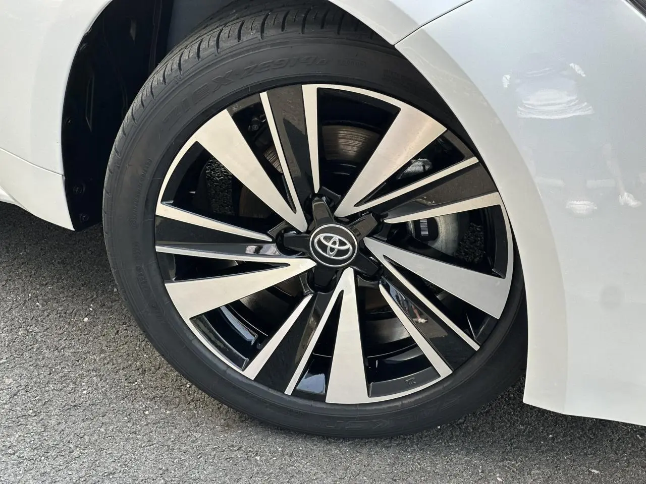 Gros plan sur la jante alliage 17 pouces bicolore noir et argent du Toyota Corolla Touring Sport blanc neige.