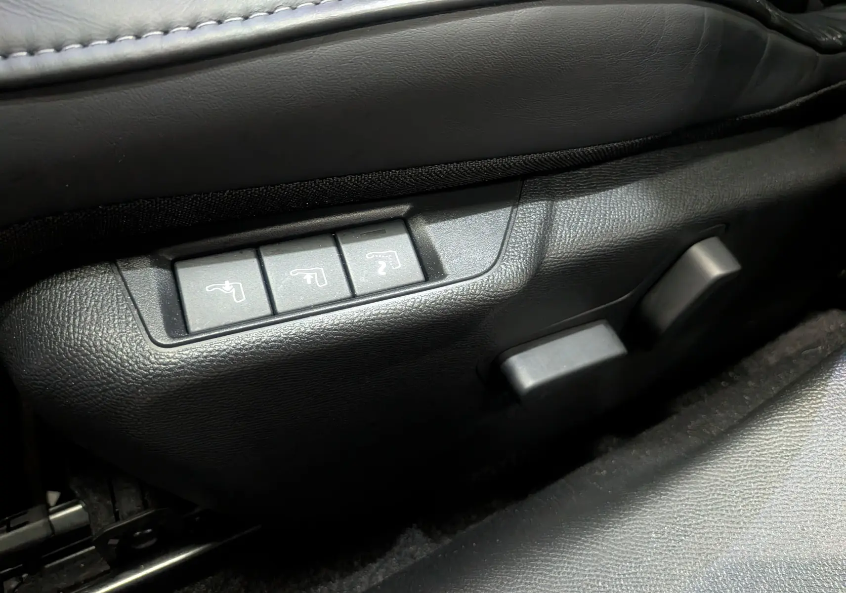 Détail des commandes de réglage électrique des sièges en cuir noir dans une DS3 PureTech 2024.