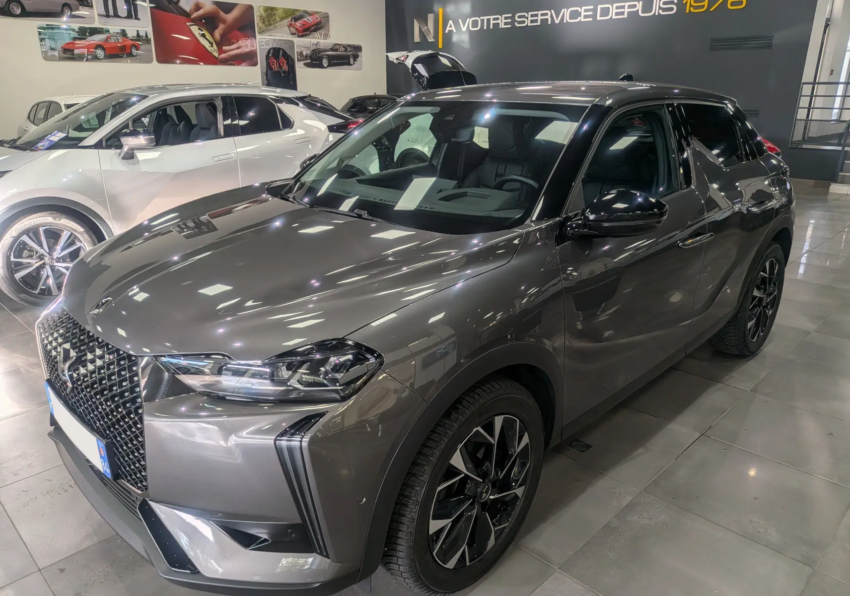 DS3 gris Platinium en 3/4 avant droit, soulignant sa calandre distinctive et ses jantes noires bicolores.