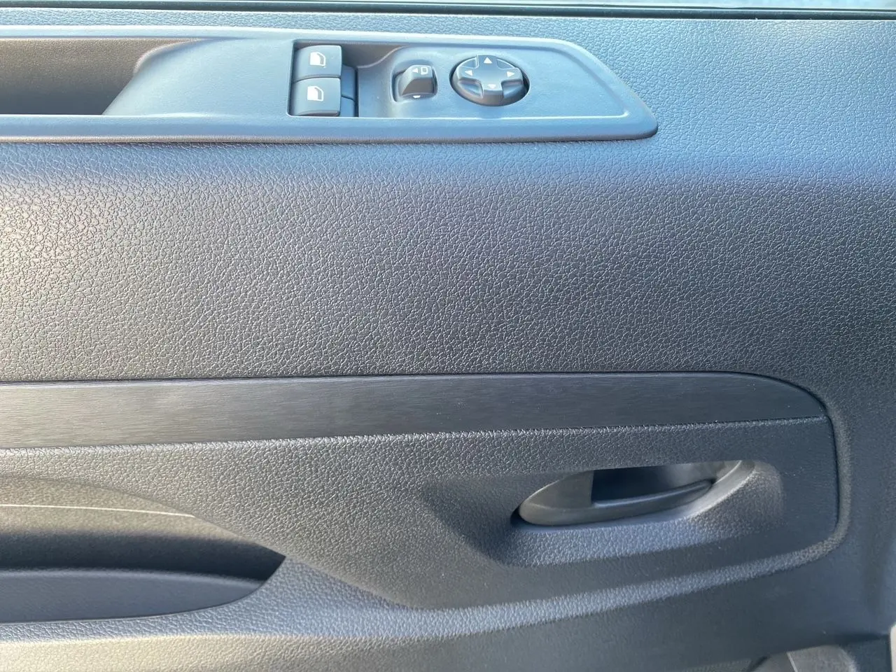 Poignée intérieure et commandes de lève-vitres sur la porte côté conducteur d'un Citroën Jumpy XL gris acier 2025.