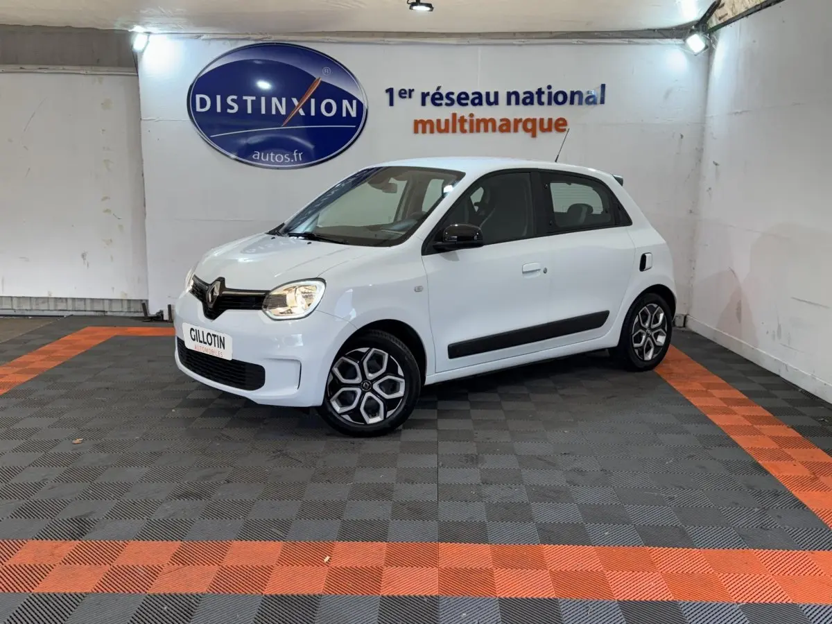 Renault Twingo Equilibre blanc vue 3/4 avant droit en intérieur, avec jantes spécifiques et rétroviseurs noirs.