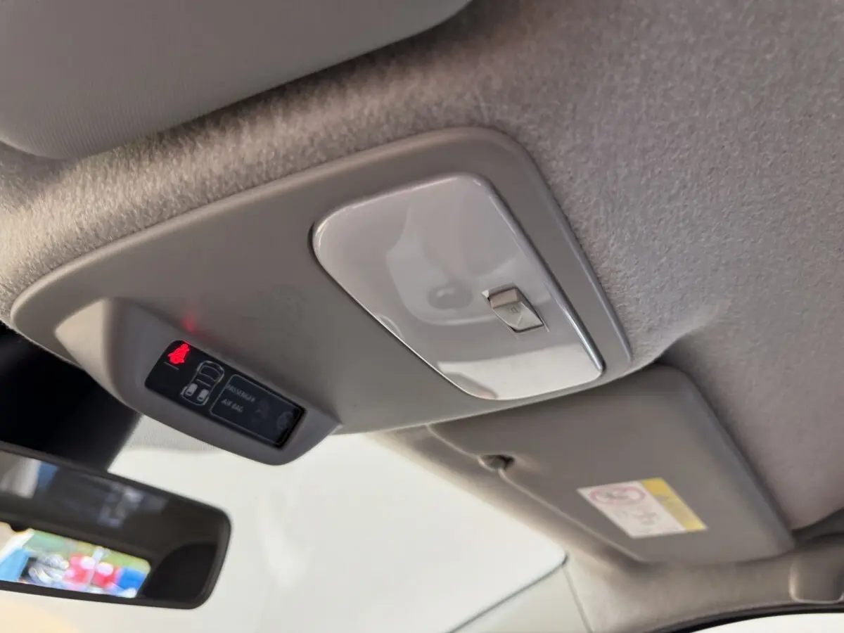 Vue intérieure rapprochée du plafonnier et du témoin d'airbag passager allumé dans une Renault Twingo blanche 2022.