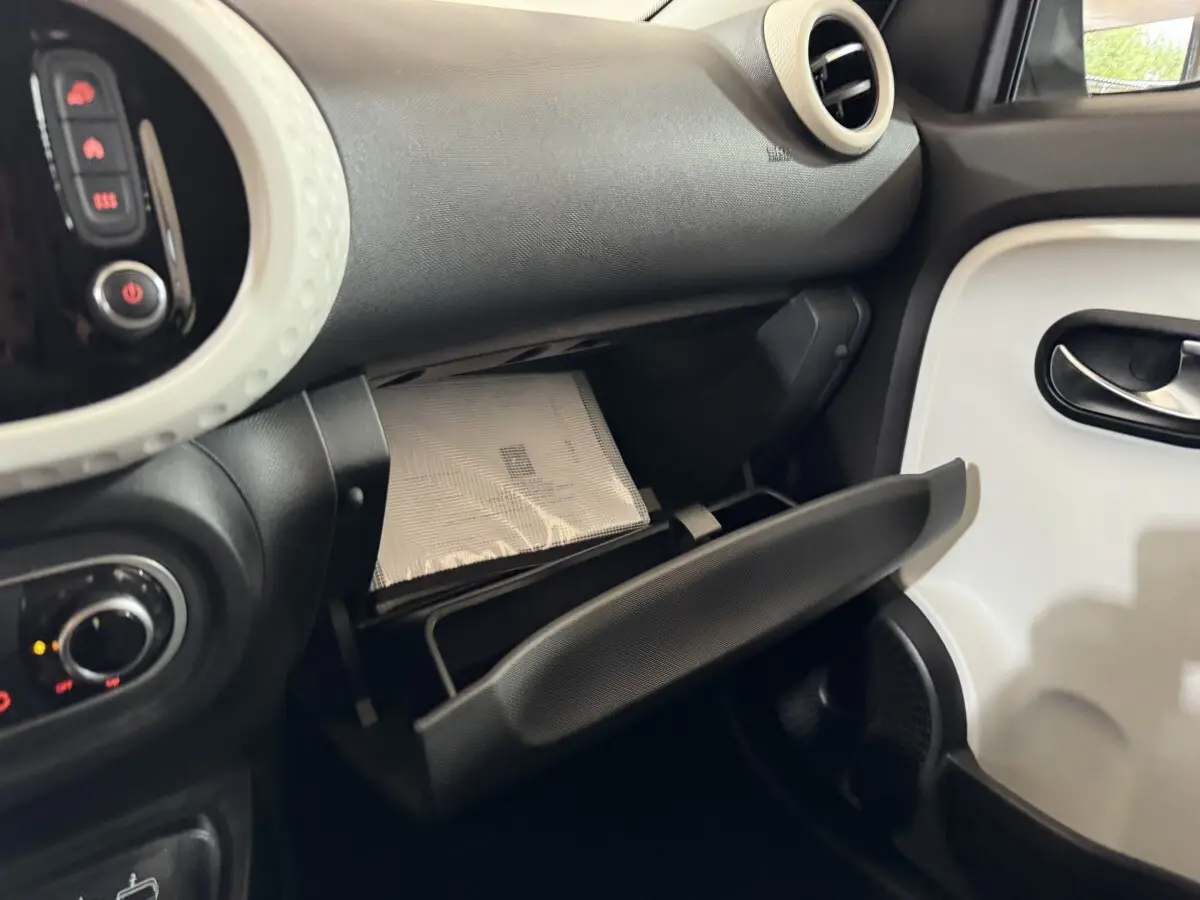 Intérieur de la Renault Twingo blanc, vue côté passager avec boîte à gants ouverte et tableau de bord noir.