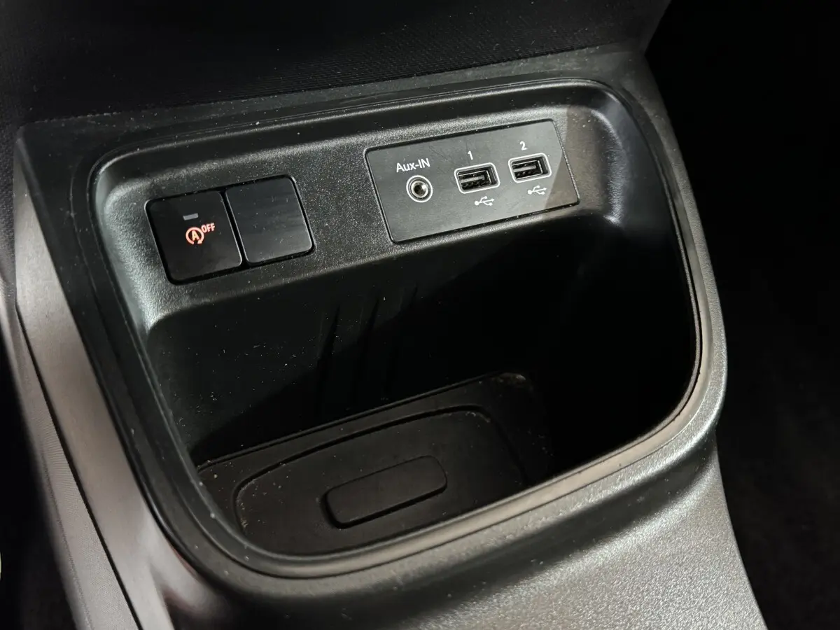 Gros plan sur la console centrale noire de la Renault Twingo blanche, montrant ports USB et bouton de désactivation start-stop.