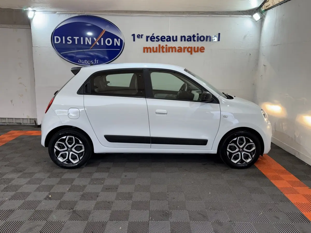 Profil côté gauche d'une Renault Twingo blanche 2022, version Equilibre SCe 65, avec jantes distinctives et poignées intégrées.