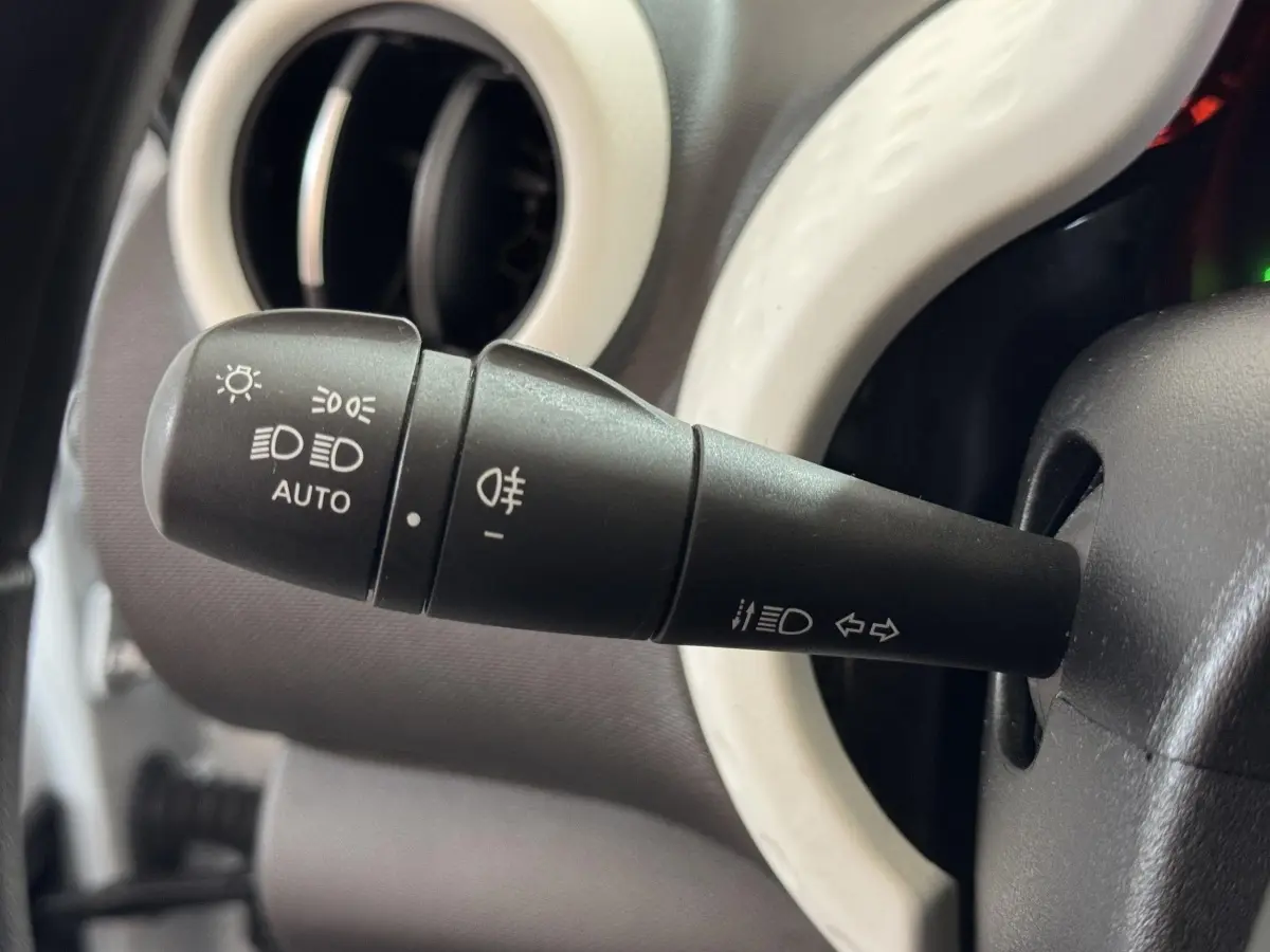 Gros plan sur la commande des phares noire avec anneau blanc du tableau de bord d'une Renault Twingo blanche 2022.