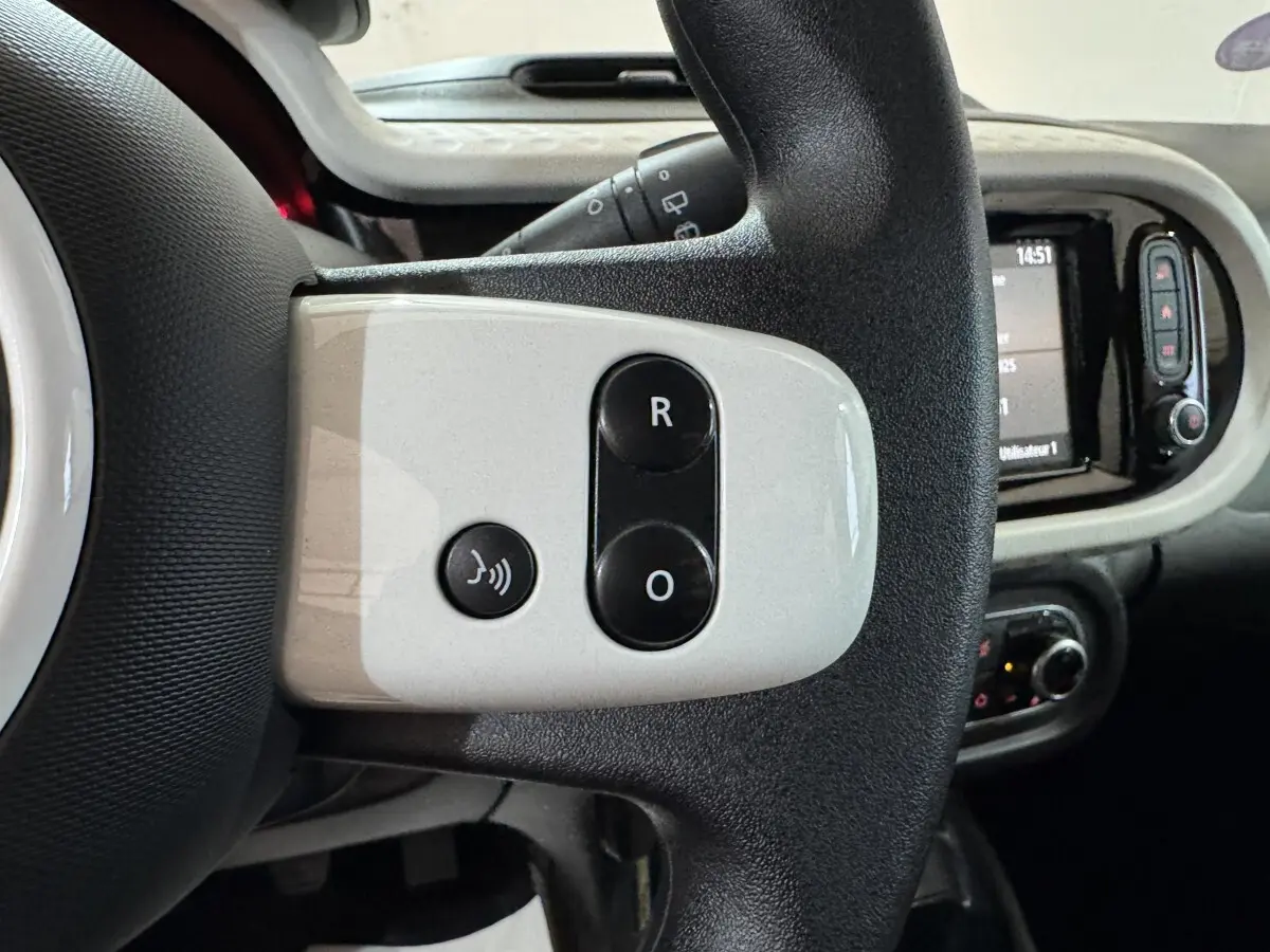 Gros plan sur la partie gauche du volant noir et blanc de la Renault Twingo 2022 avec commandes vocales et régulateur.