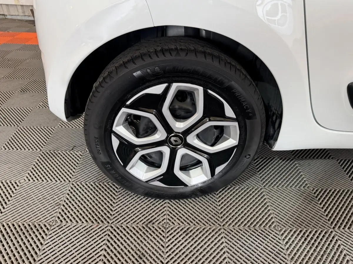 Gros plan sur la roue avant gauche blanche d’une Renault Twingo 2022 avec jante noire et argentée au design géométrique.