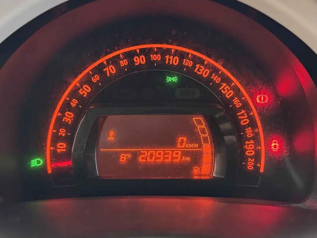 Gros plan sur le tableau de bord numérique éclairé en rouge de la Renault Twingo blanche, affichant 20939 km et 8°C.