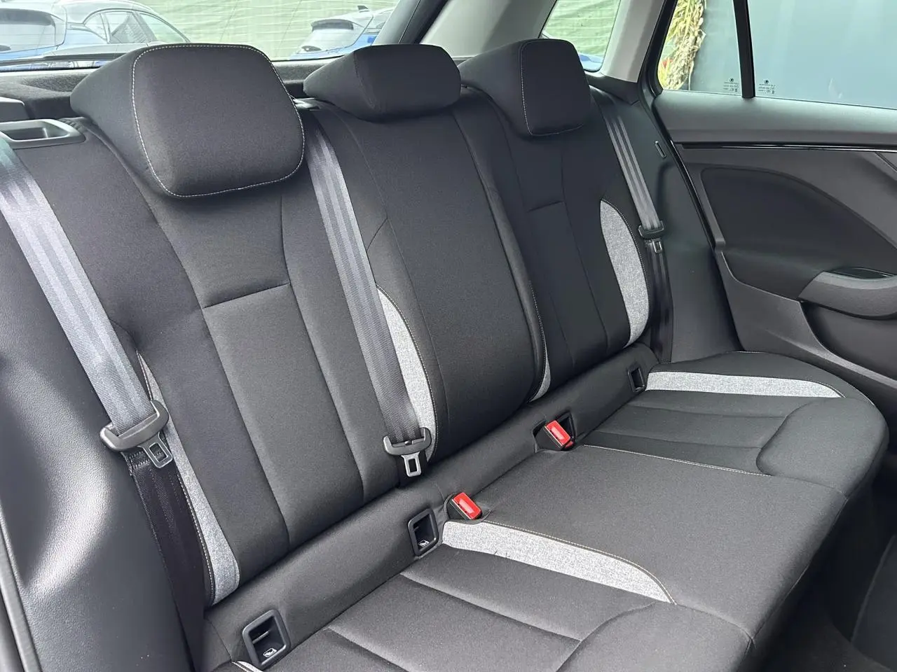 Vue latérale de la banquette arrière noire et grise du Skoda Kamiq 2025 avec ceintures et appuie-têtes intégrés.