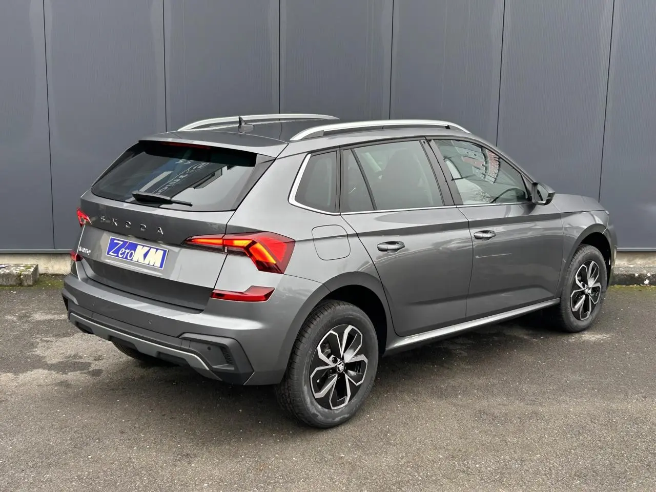 Vue 3/4 arrière droite d’un Skoda Kamiq gris graphite avec jantes alliage et vitres surteintées.