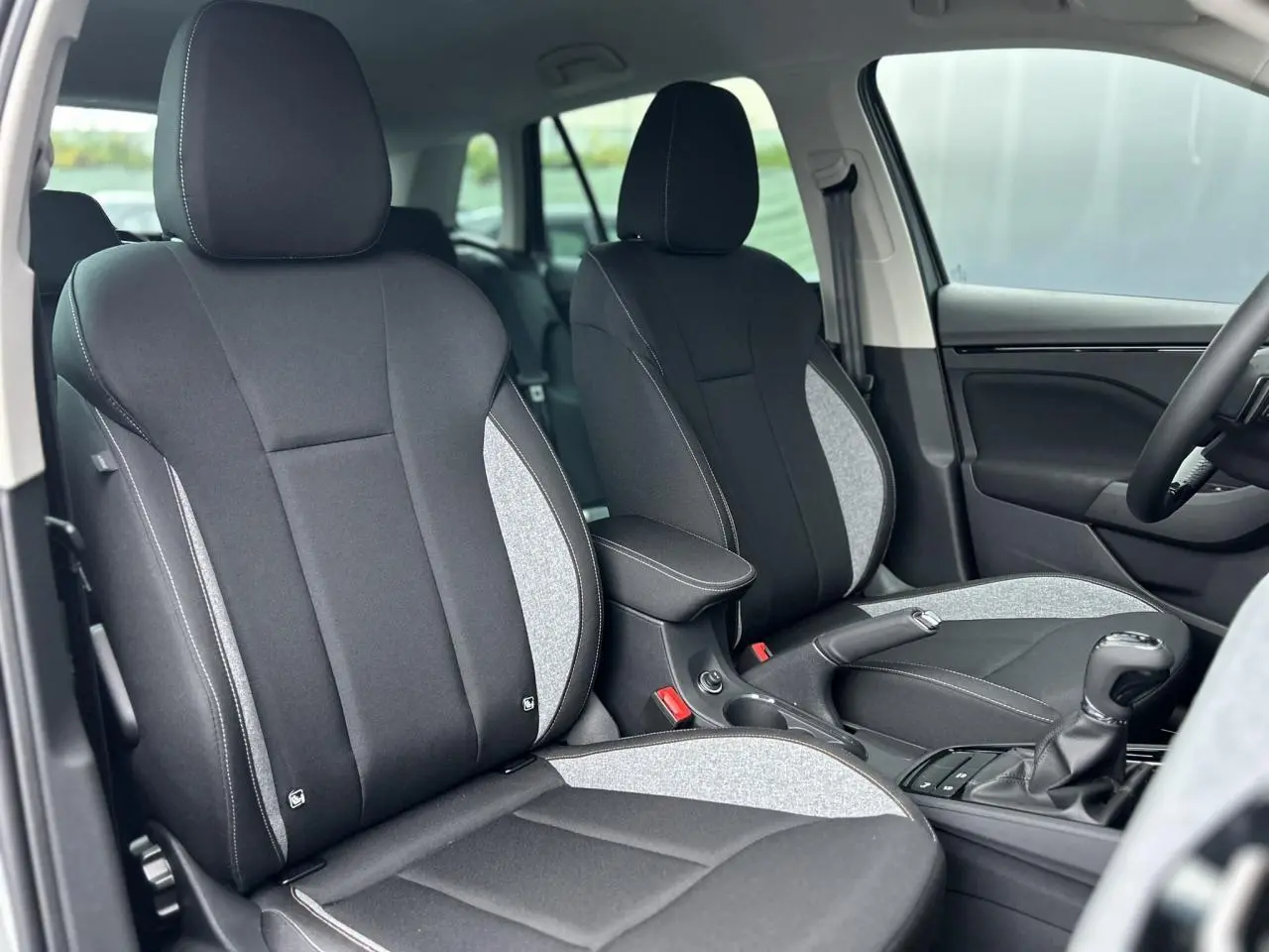 Vue intérieure côté avant droit montrant les sièges bi-ton gris et noir du Skoda Kamiq 2025 TSI 116 DSG7 Selection.