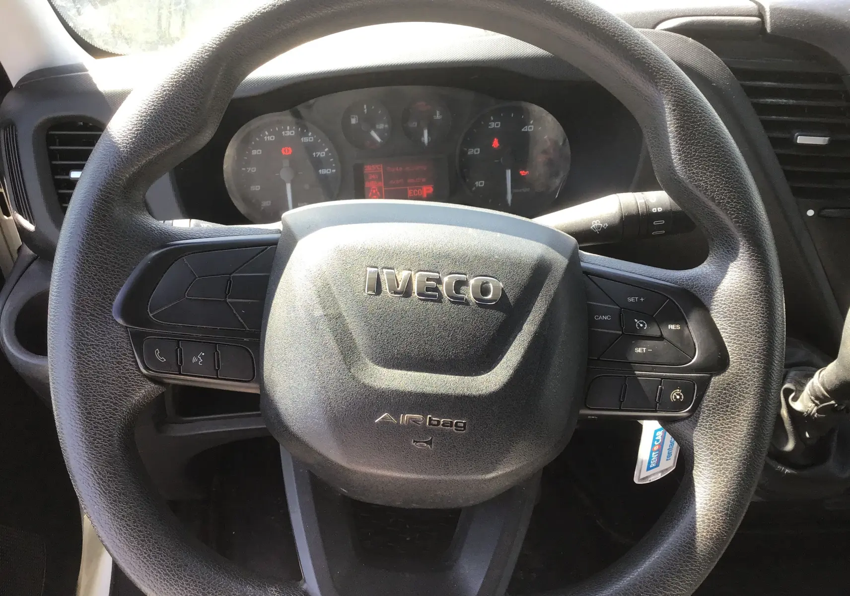 Vue rapprochée du volant noir marqué IVECO du Daily Chassis Cabine 35C14 blanc, avec tableau de bord en arrière-plan.