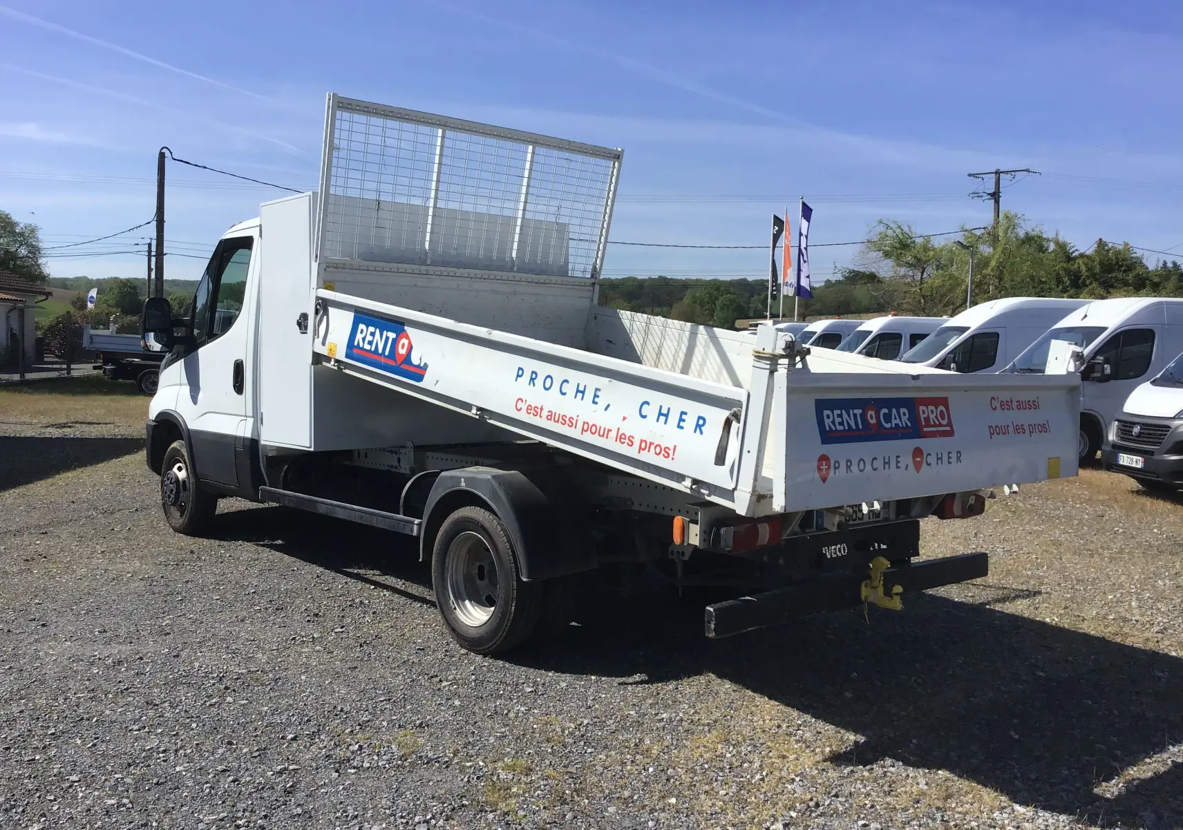 IVECO Daily Chassis Cabine blanc vu 3/4 arrière droit avec benne JPM en acier relevée et coffre latéral.