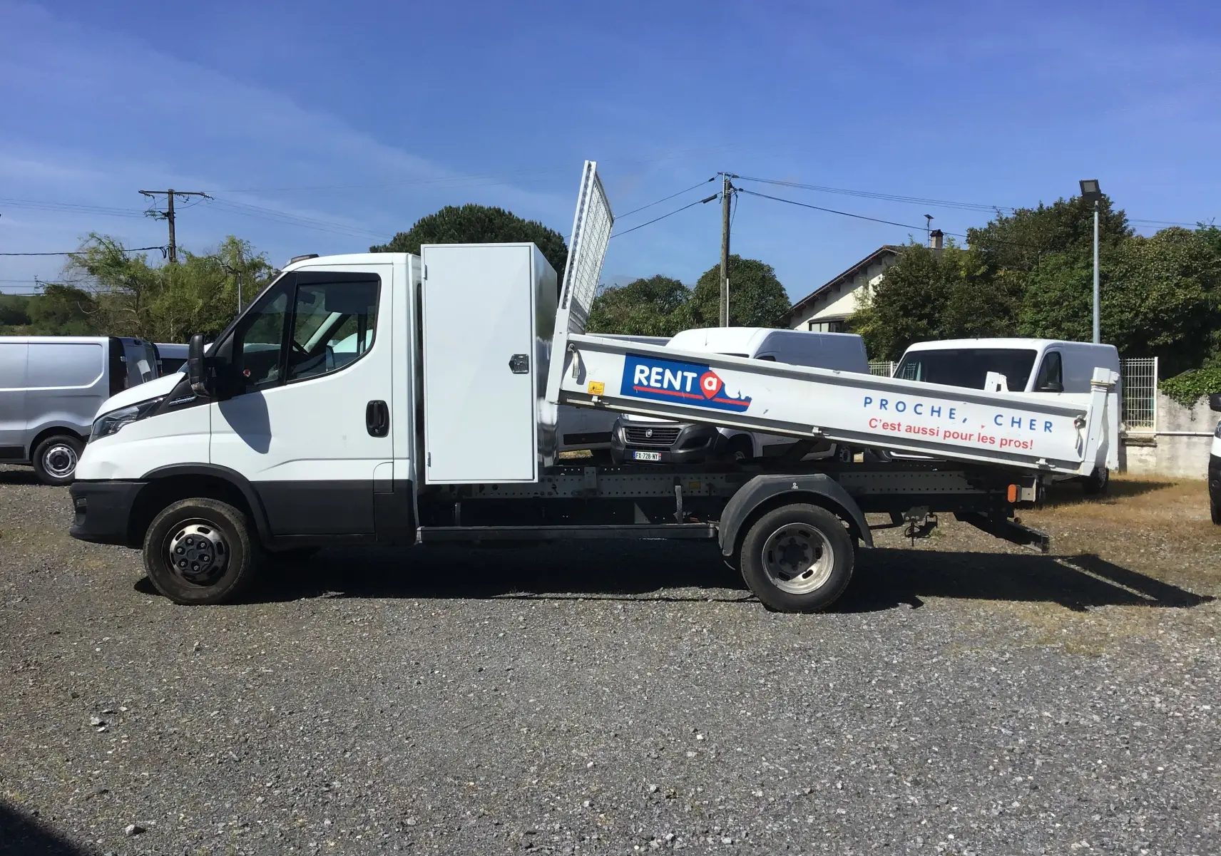 Vue latérale gauche d’un Iveco Daily blanc 35C14 avec benne basculante JPM en acier et coffre latéral fermé.