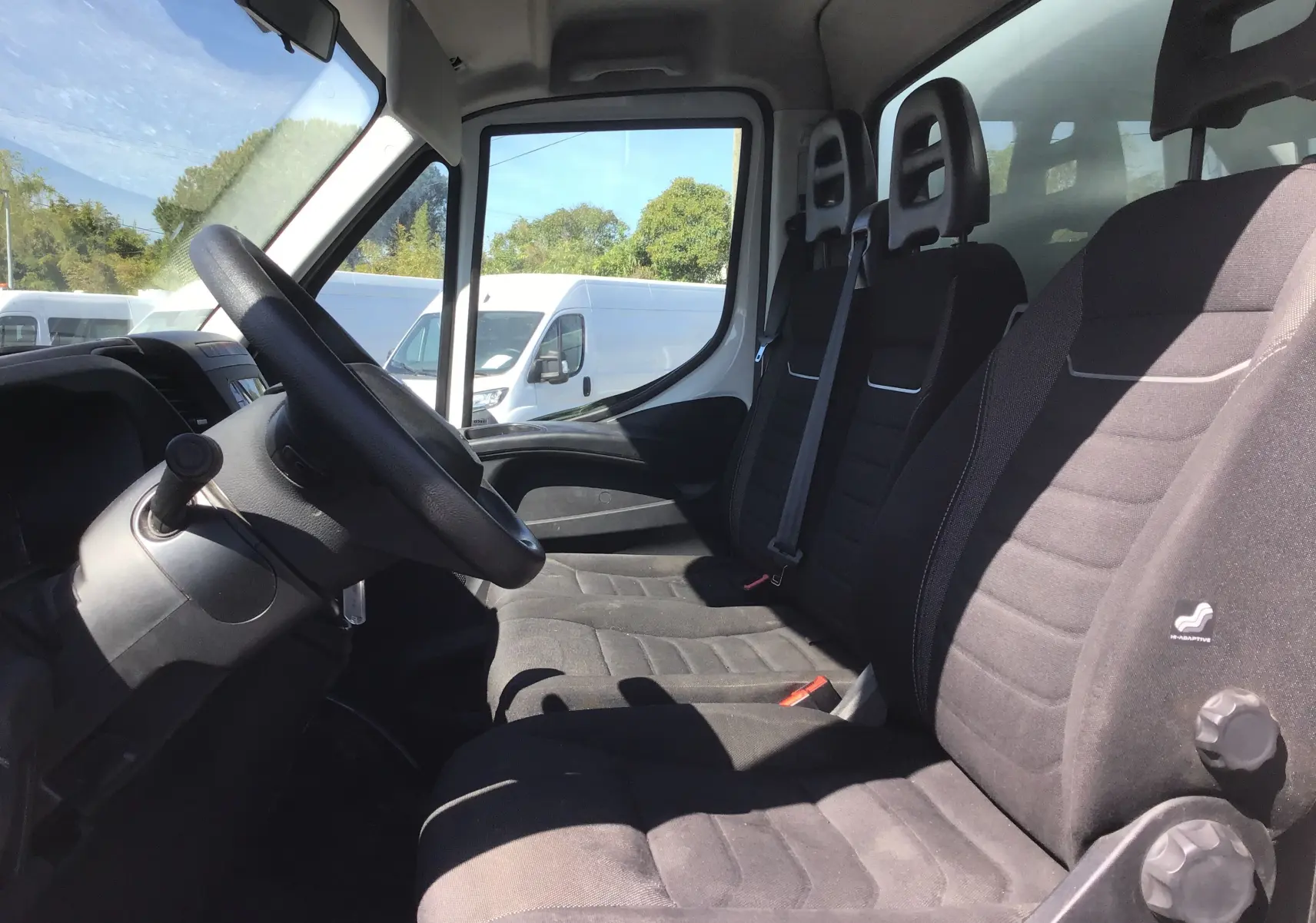 Vue intérieure côté conducteur de l'Iveco Daily Chassis Cabine 35C14 blanc, montrant les sièges noirs et le volant.