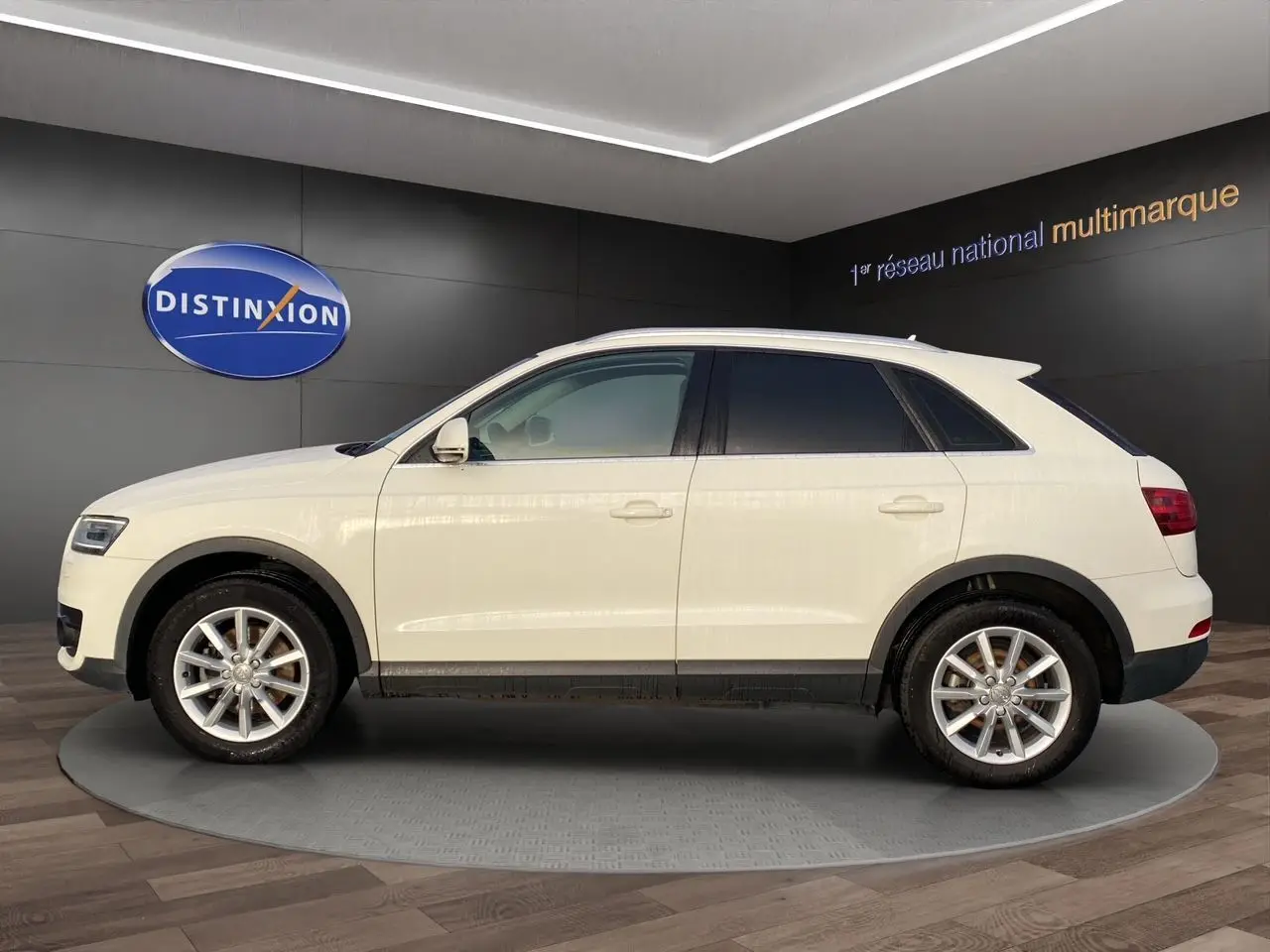Audi Q3 blanc vue de profil côté gauche avec vitres arrière surteintées dans un showroom.