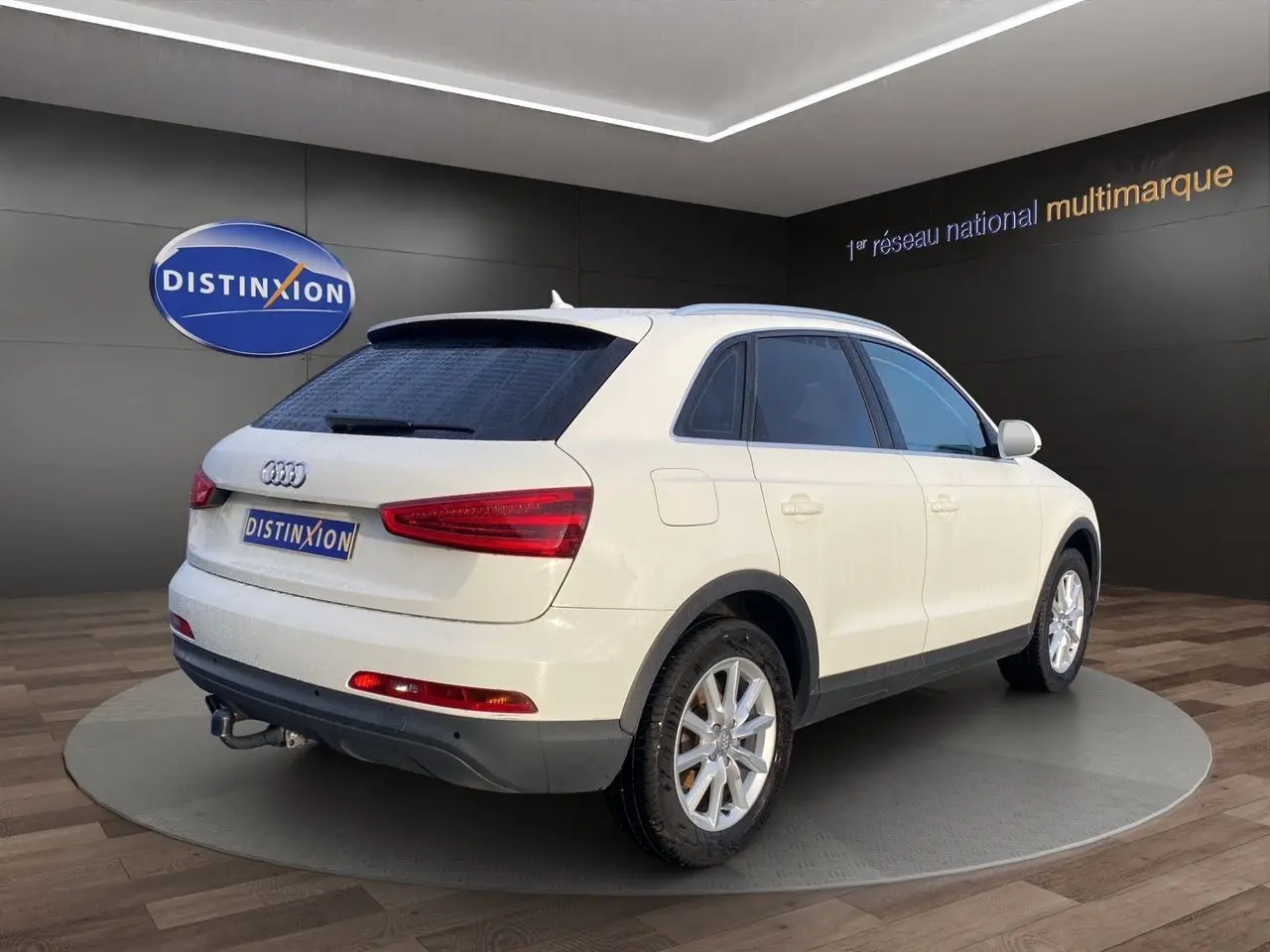 Audi Q3 blanc en 3/4 arrière droit avec vitres arrière surteintées, attelage et jantes alliage 17 pouces.