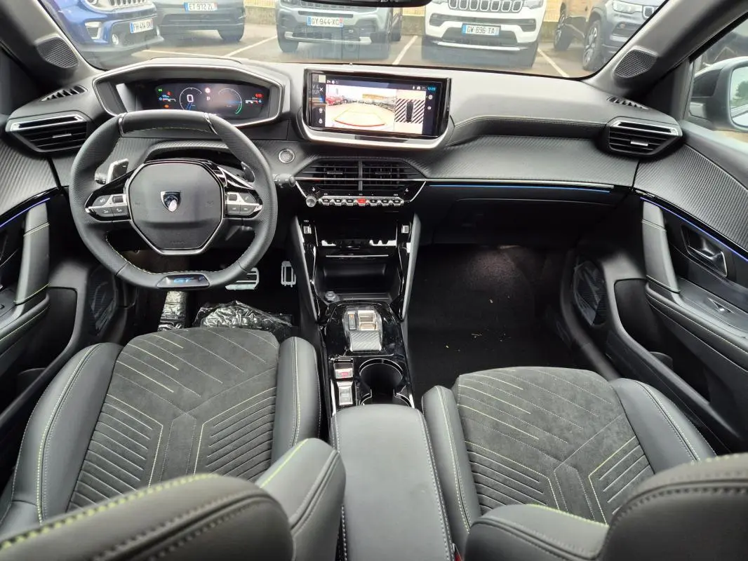 Vue intérieure avant du Peugeot 208 Hybrid 110 e-DCS6 GT gris, avec volant compact, écran tactile et cockpit numérique.