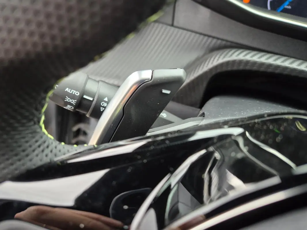 Gros plan sur la palette de changement de vitesse et le commodo d’éclairage dans l’habitacle d’une Peugeot 208 gris 2025.