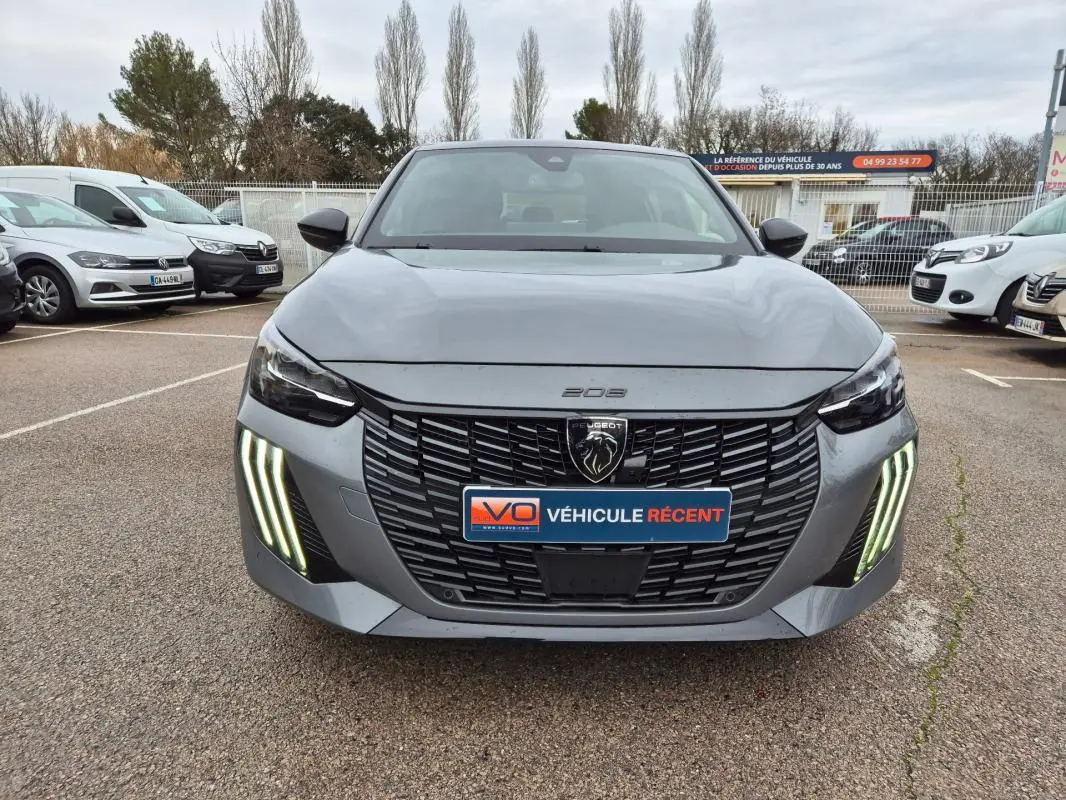 Vue avant d'une Peugeot 208 gris métallisé avec calandre noire et feux diurnes LED verticaux allumés.