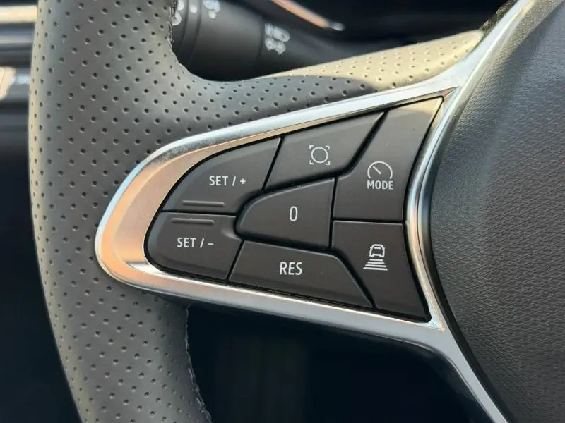 Gros plan sur les commandes noires du volant côté gauche du Renault Captur gris Rafale métallisé, boutons multifonctions.