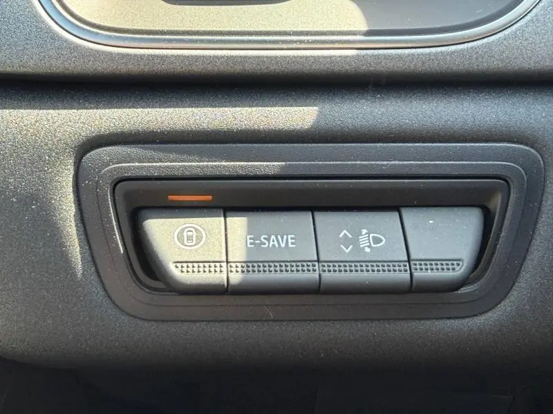 Gros plan sur les boutons de commande E-SAVE et réglage des phares du tableau de bord du Renault Captur gris Rafale.