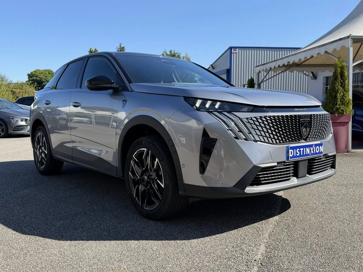 Vue 3/4 arrière droite d’un Peugeot 3008 gris clair hybride avec jantes noires et toit noir brillant.