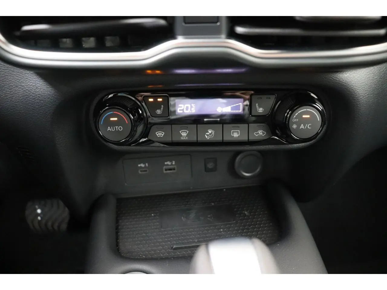 Vue rapprochée du tableau de bord de la Nissan Juke 2026, montrant la commande de climatisation automatique et les ports USB.