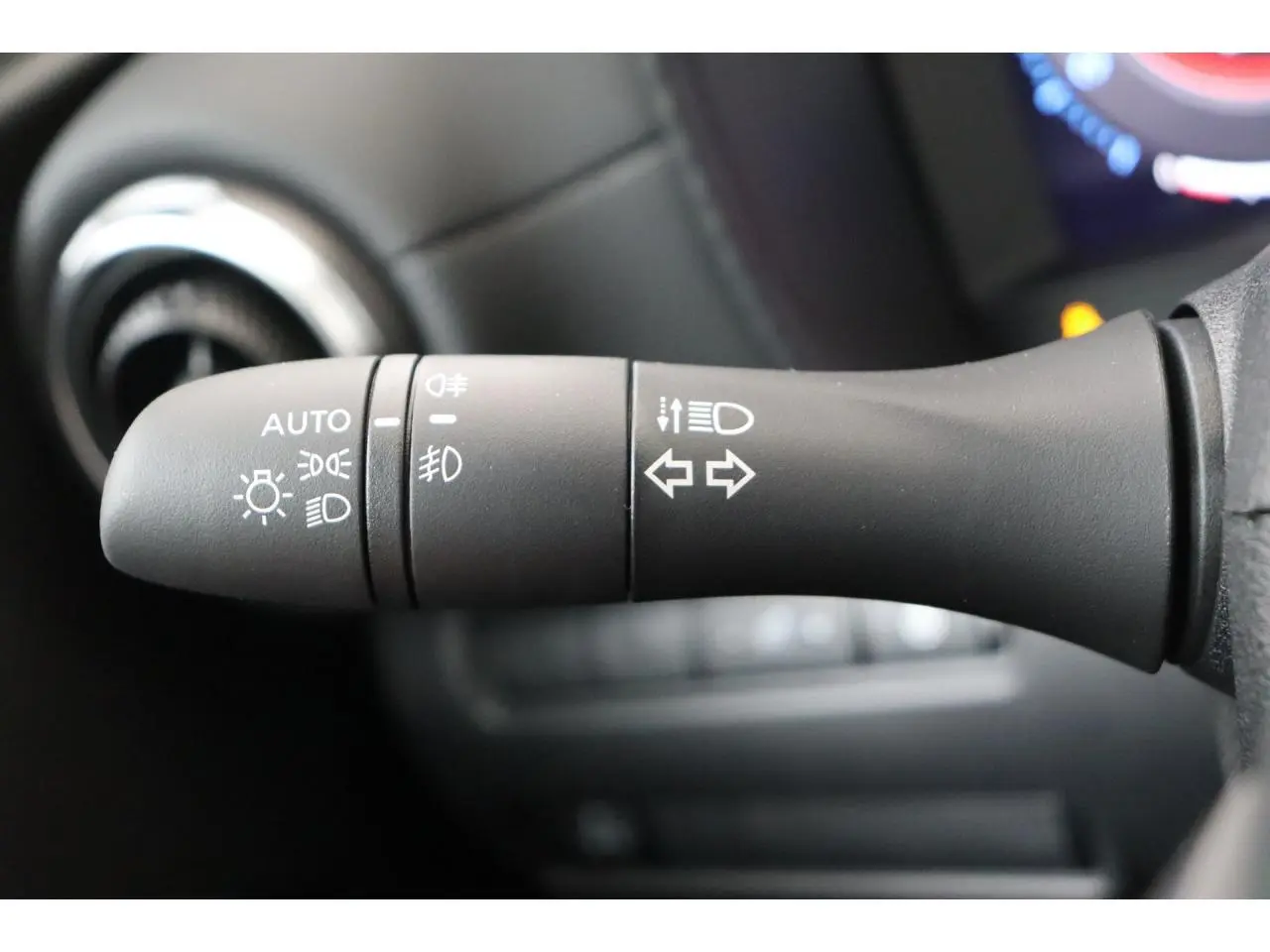 Gros plan sur la commande des feux et clignotants dans l'habitacle du Nissan Juke hybride 2026.