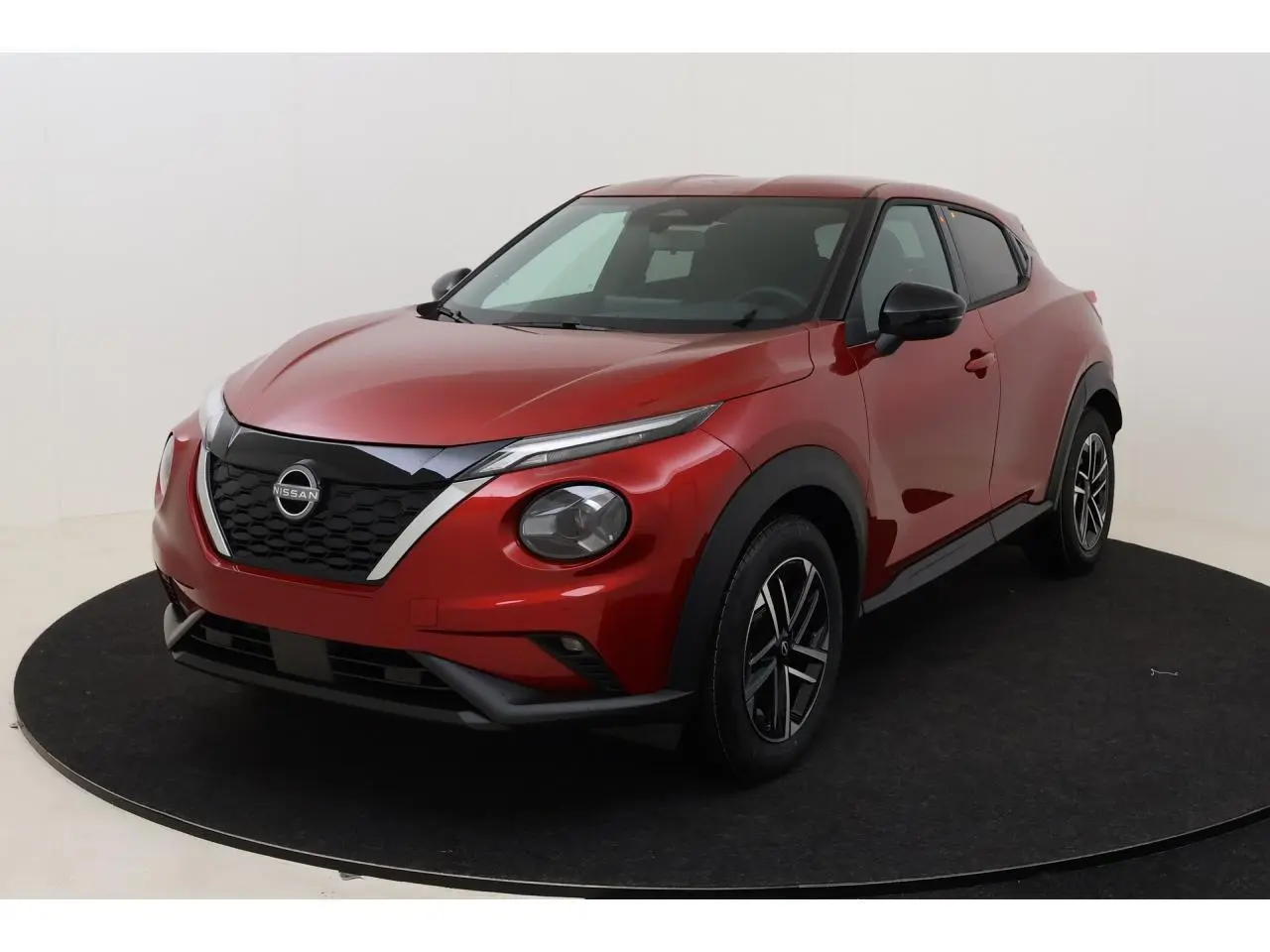 Nissan Juke 2026 rouge Fuji Sunset en 3/4 avant droit, avec calandre noire et jantes alliage 17 pouces.