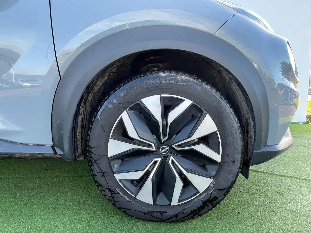 Gros plan sur la roue avant gauche du Nissan Juke 2024 gris ceramic avec jante alliage noire et argentée.