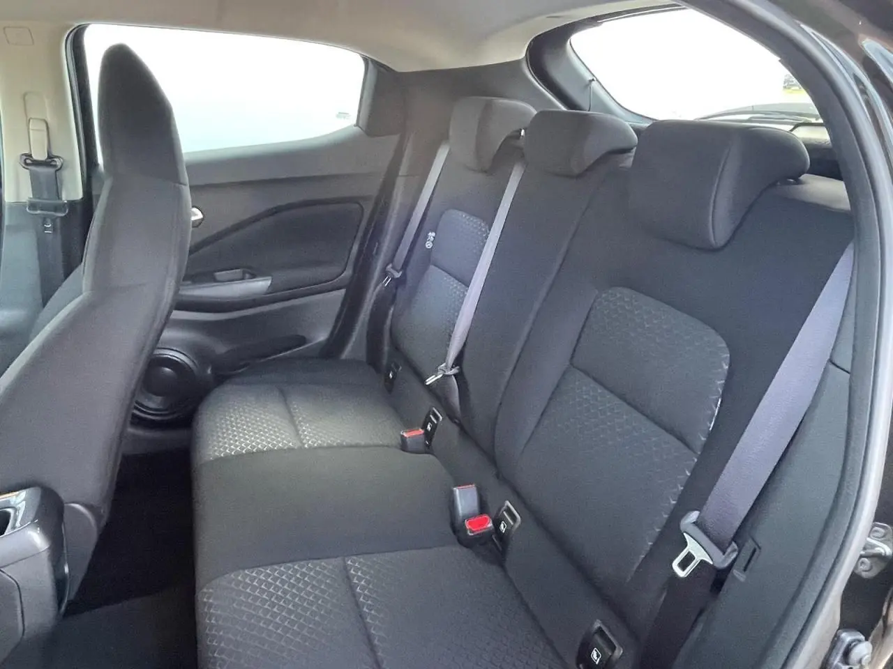 Vue intérieure côté droit montrant la banquette arrière noire et les appuis-tête du Nissan Juke II 2024 gris ceramic.