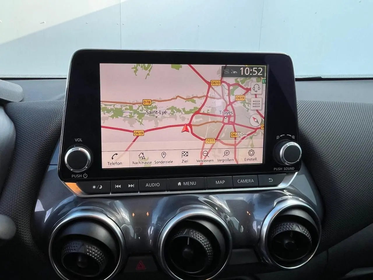 Écran tactile central avec navigation affichée et commandes rondes d’aération sur tableau de bord gris métallisé du Nissan Juke 2024.