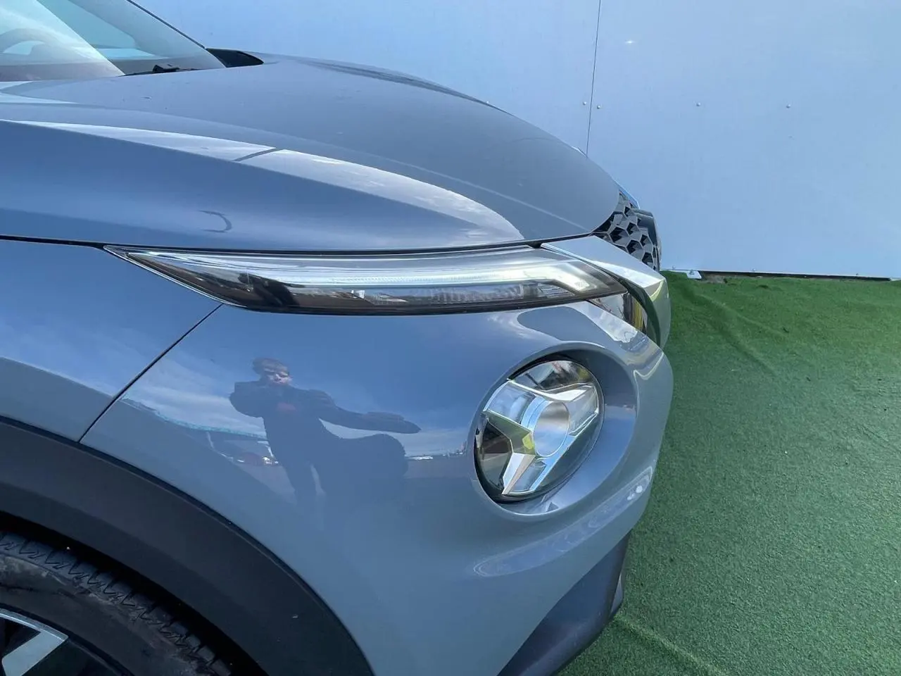Gros plan sur l'avant droit du Nissan Juke 2024 gris ceramic, mettant en valeur son phare rond et sa calandre distinctive.