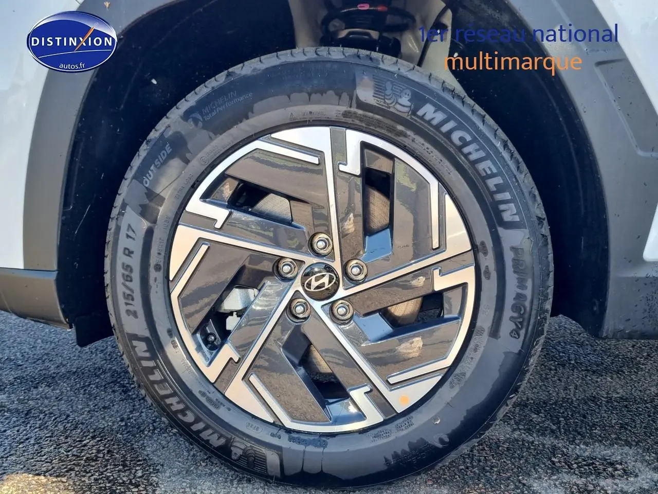 Gros plan sur la roue avant gauche du Hyundai Tucson blanc atlas avec jante alliage 17 pouces au design moderne.