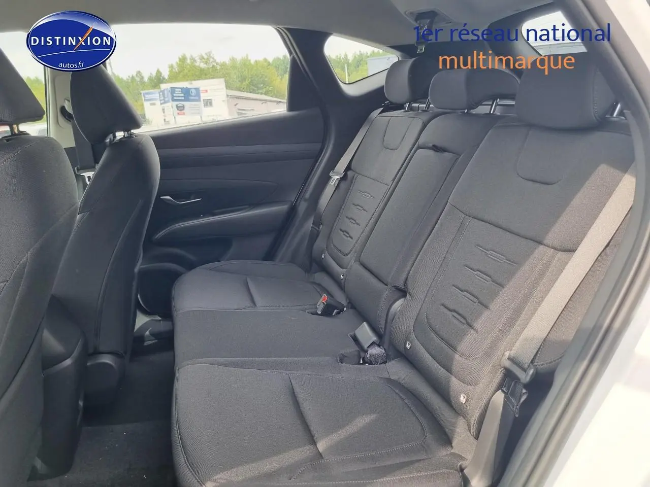 Vue latérale des sièges arrière noirs du Hyundai Tucson 2025 blanc atlas, avec ceintures et appuie-têtes visibles.