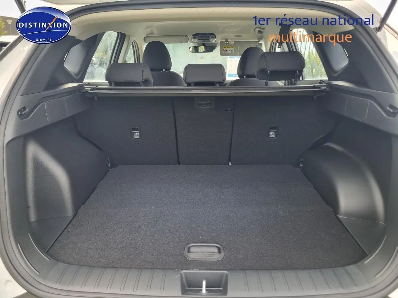 Coffre ouvert du Hyundai Tucson blanc atlas vu de l'arrière, montrant l'espace de chargement et la banquette arrière.