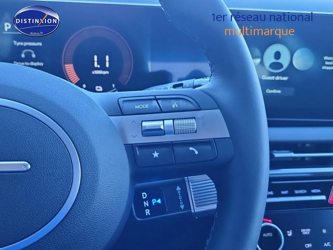 Gros plan sur le volant cuir noir du Hyundai Tucson blanc atlas 2025, avec commandes multifonctions et écran tactile en arrière-plan.